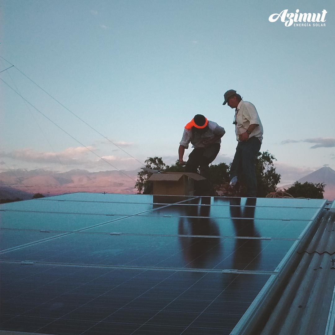 Técnicos instalando paneles solares sobre un techo al atardecer