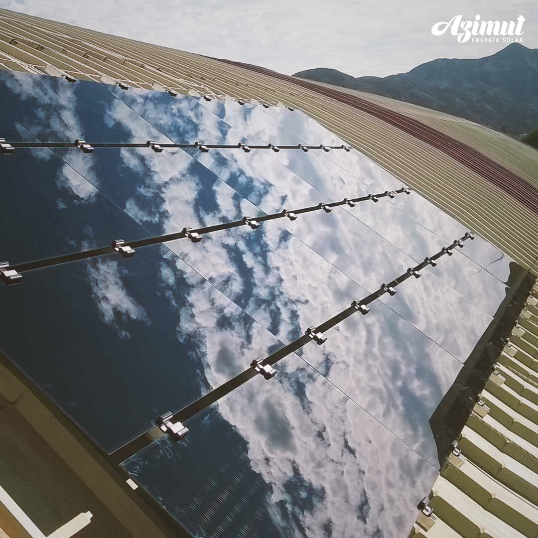 Paneles solares sobre un techo de zinc reflejando el cielo
