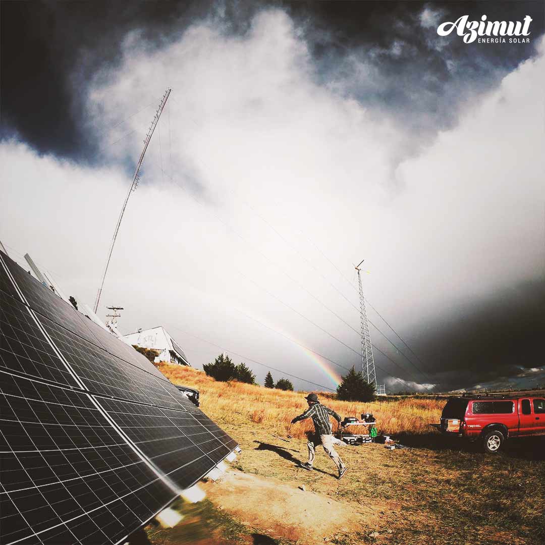 Paneles solares en un terreno rural con un arcoíris de fondo
