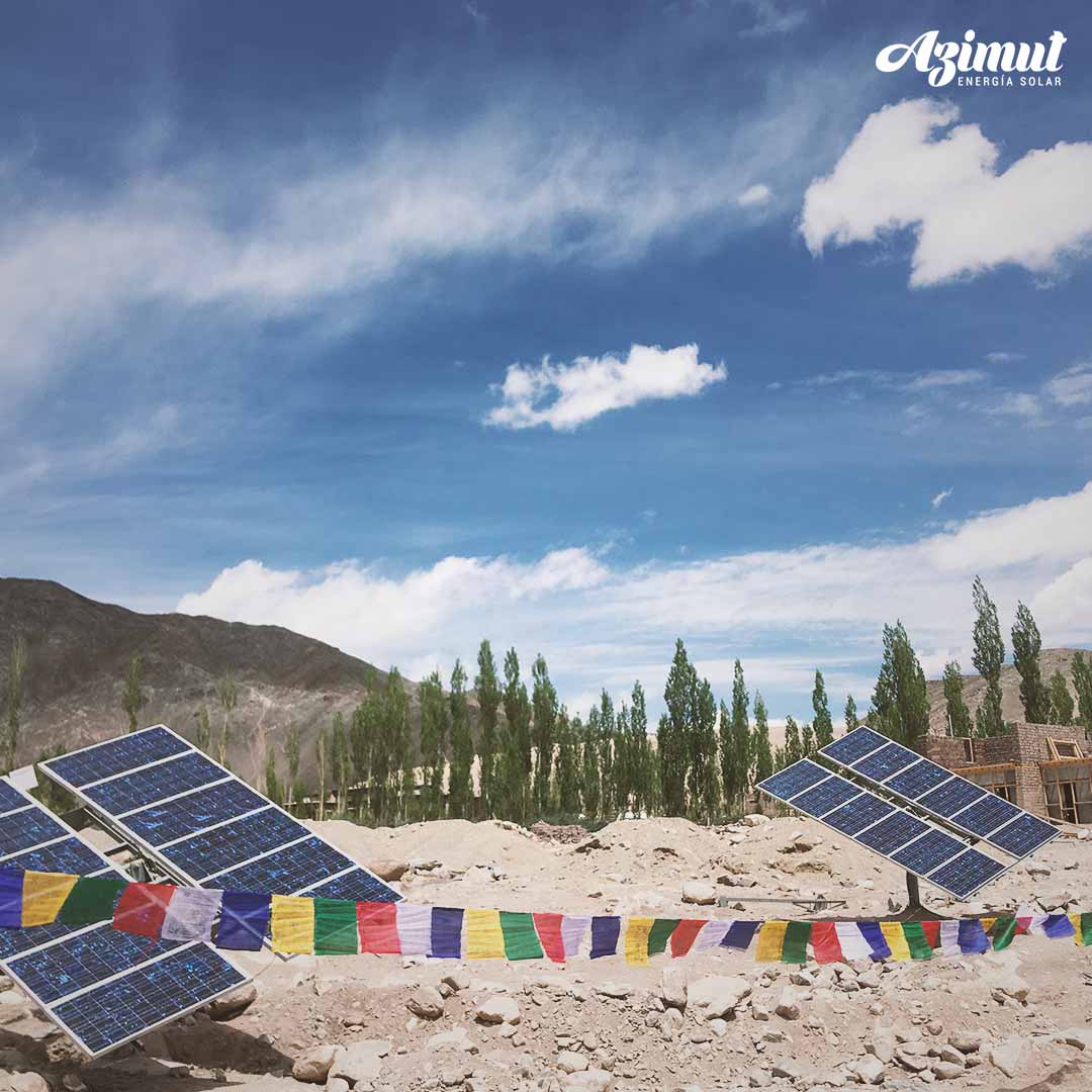 Paneles solares instalados en terreno con cerros y álamos de fondo