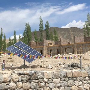 Paneles solares sobre estructura en terreno junto a una construcción en India